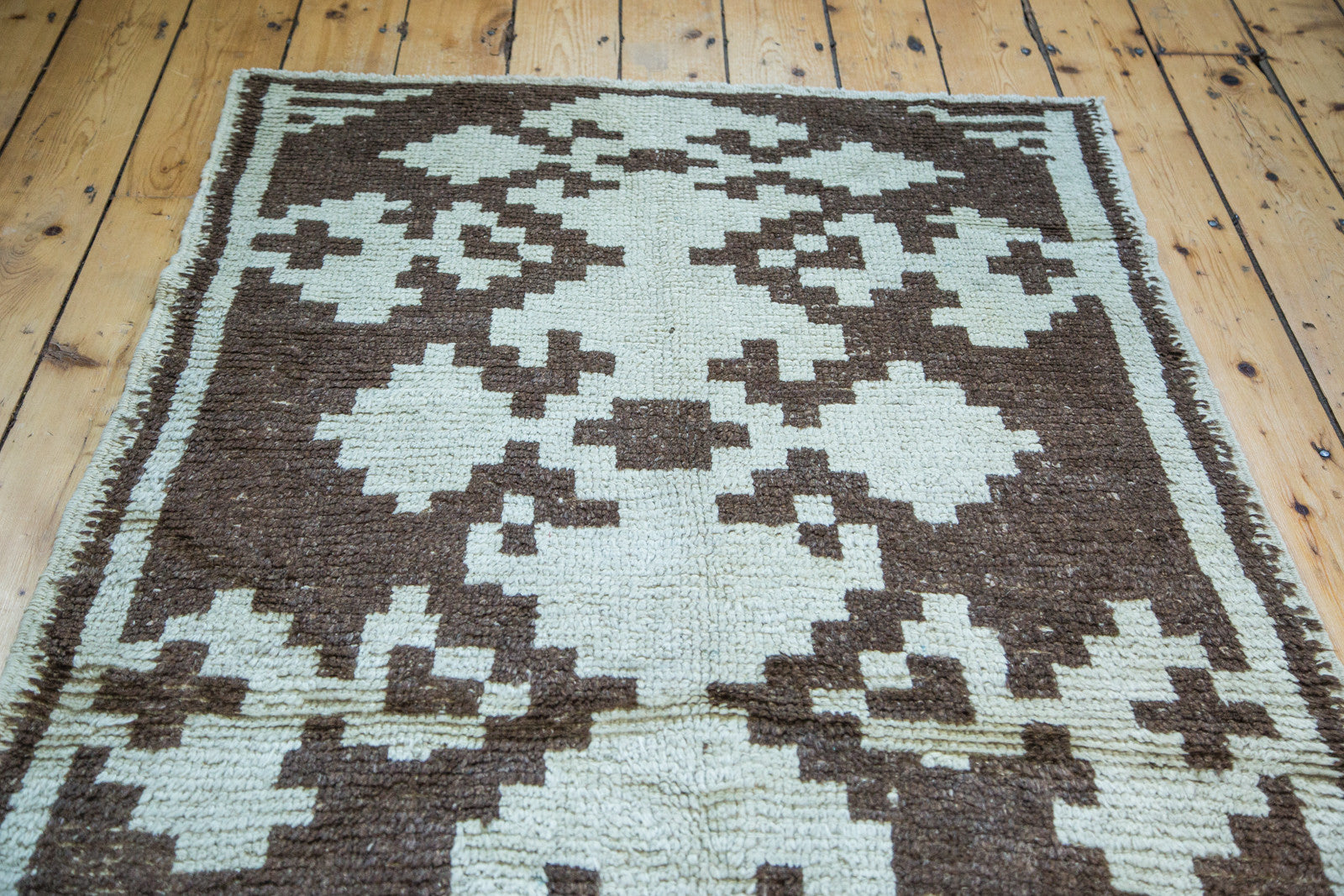 Corner of vintage Tulu rug displaying shaggy ivory and charcoal geometric pattern.